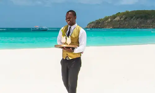 A butler at Sandals Grande Antigua brings drinks to ocean chairs (c)Sandals