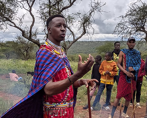 A Maasai man explains his way of life during a tribal village visit on an experiential travel vacation 