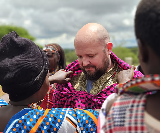 Jeof Oyster receiving a traditional mashuka while visiting a Maasai tribe, while on safari in Kenya, a true experiential travel moment. 