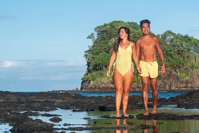A couple walks along a rocky beach