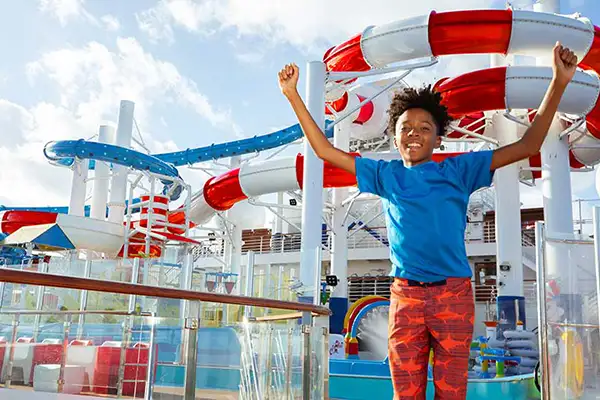A boy celebrates by the water slides on a Carnival ship