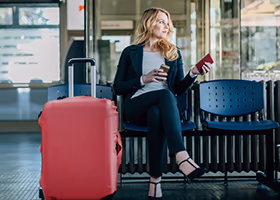 A business woman waits with her suitcase
