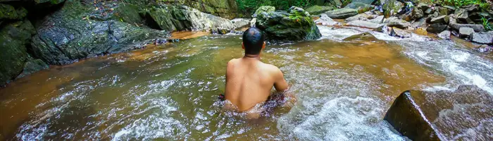 Young man relaxes in a forest hot spring