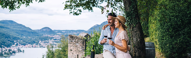 A mature couple sips wine while looking over the river