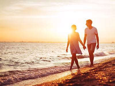 Couple walking along the beach at sunset