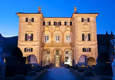 Exterior at night of luxury villa with private pool and tennis court in Tuscany, Italy