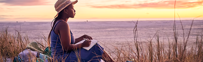 A woman journals by the sea